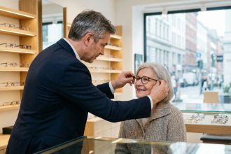 Opticien professionnel ajustant des lunettes à une cliente âgée