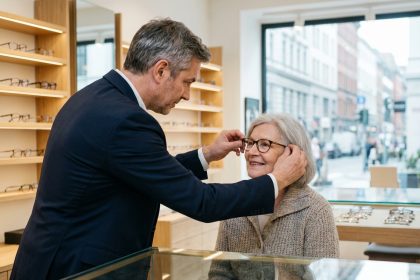 Opticien professionnel ajustant des lunettes à une cliente âgée